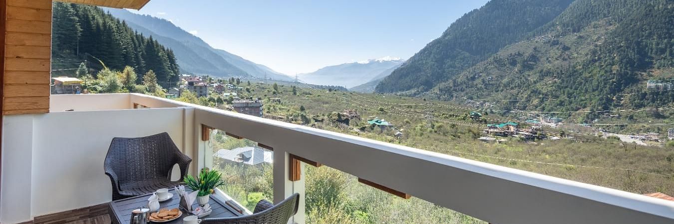 Image of a balcony with a table and chairs overlooking a scenic mountain valley  | DLS Serenity Resort and Spa